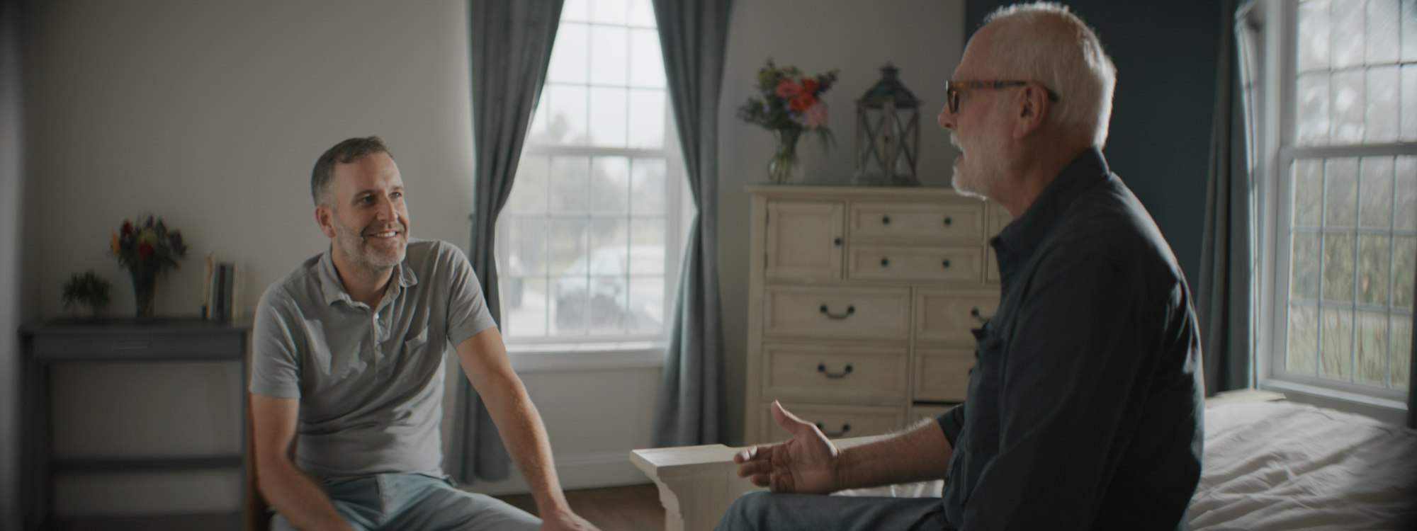 Two men in relaxed conversation in a bright room
